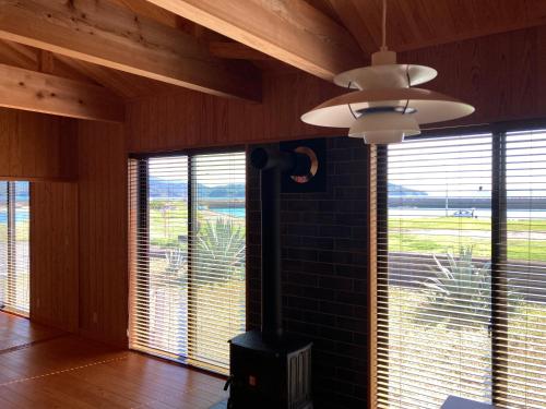 a living room with a ceiling fan and large windows at Amakusa Ebisu House -天草 えびすHOUSE , 港の前に建つ自然素材の一軒家- in Amakusa