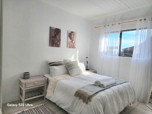 a white bedroom with a bed and a window at 87 on Sunbird B in Langebaan