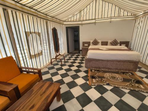 a bedroom with a bed and a checkered floor at Jaisalmer Landscape Camp in Jaisalmer