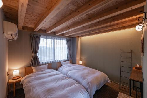 a bedroom with two beds and a window at TORIKKA Stay -海だけが見える宿- in Sumoto