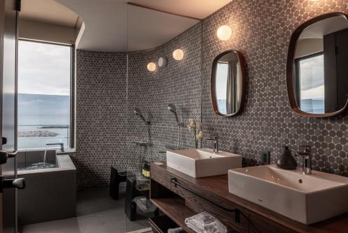a bathroom with two sinks and a tub and mirrors at TORIKKA Stay -海だけが見える宿- in Sumoto