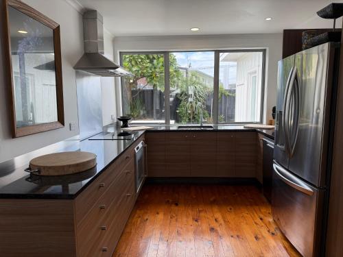 a kitchen with a stainless steel refrigerator and a window at Ocean Front East End Beach House in New Plymouth