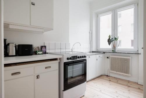 een witte keuken met witte kasten en een fornuis bij Cozy home in charming suburb in Sundbyberg