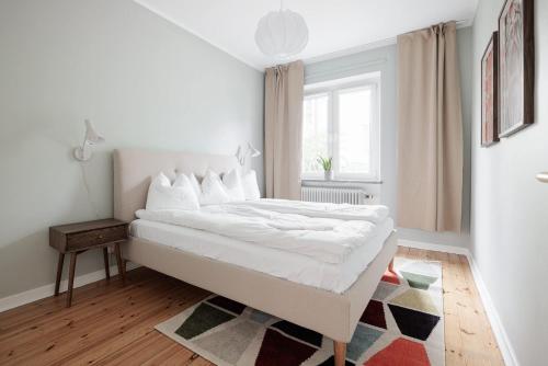 een witte slaapkamer met een groot bed en een tapijt bij Cozy home in charming suburb in Sundbyberg