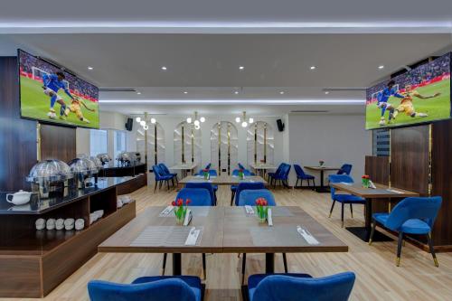 a dining room with tables and blue chairs at Vendome Plaza Hotel in Dubai