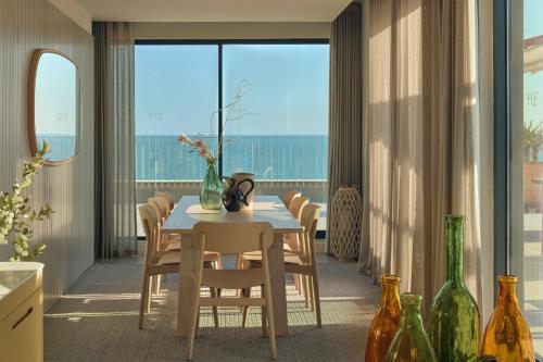 a dining room with a table and chairs and a large window at ME Sitges Terramar in Sitges