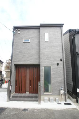 a gray house with a wooden garage door and stairs at Green Palace Tennoji in Osaka
