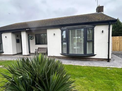 a white house with black windows and a bench at Lanrest in Talacre