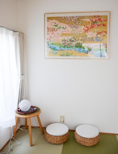 a room with two stools and a painting on the wall at Ayaka House Hirai in Tokyo