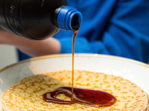 una persona vertiendo jarabe en un tazón de comida en Maek Hotel Antwerp Central - Handwritten Collection by Accor, en Amberes