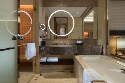 a bathroom with a tub and a sink and a mirror at Hilton Yantai Golden Coast in Yantai