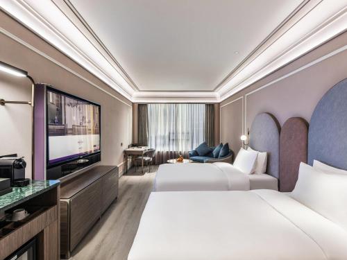 a hotel room with two beds and a flat screen tv at Mercure Nanjing Downtown in Nanjing