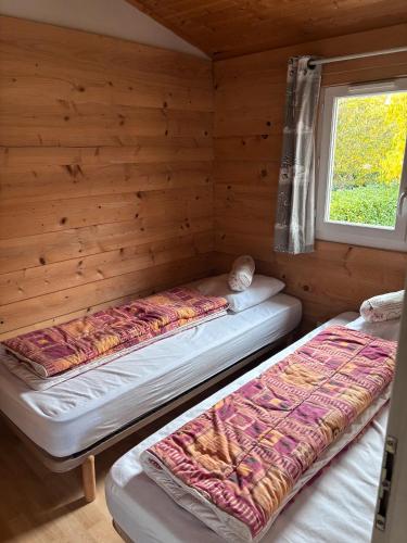 two beds in a log cabin with a window at chalet montana 5_4 pers in Roquefeuil
