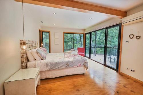 a bedroom with a bed and a large window at Ecoasis Mami Wata Rainforest Haven in Uki
