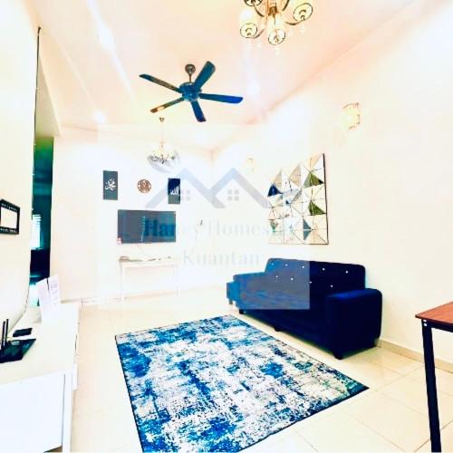 a living room with a blue couch and a rug at Haney Homestay in Kuantan