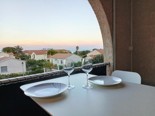 a table with two wine glasses on a balcony at studio à 100m de la plage et de la piscine in Cervione