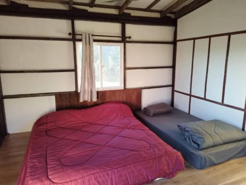a bedroom with a red bed and a window at มองนาภูคาน่านโฮมสเตย์ in Ban Thon (1)