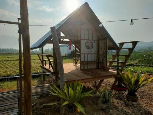 a small house with a wooden deck in a field at มองนาภูคาน่านโฮมสเตย์ in Ban Thon (1)