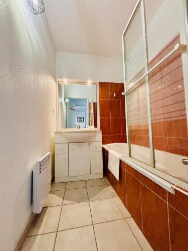 a bathroom with a sink and a tub and a mirror at Le Cersois,proche Canal du Midi et de la Mer, environnement paisible et parking privé in Cers