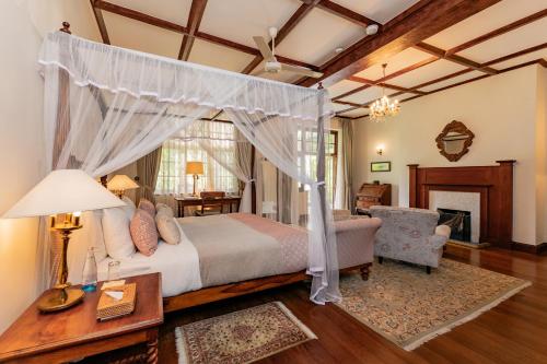 Un dormitorio con una cama con dosel y una silla. en Ceylon Tea Trails - Relais and Chateaux - All Inclusive, en Hatton