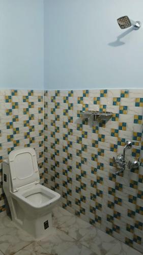 a bathroom with a toilet and a mosaic wall at The Heaven Town in Hawālbāgh