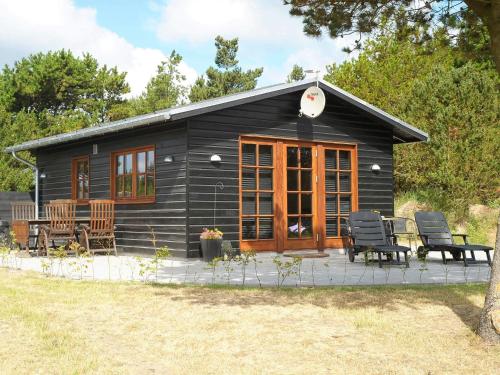 a small black cabin with chairs and a patio at Seaside Escape in Ho Bay - By Traum Ferienwohnungen in Ho