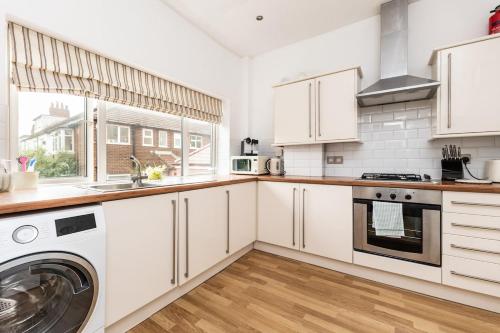 a kitchen with white cabinets and a washer and dryer at Street Lane Roundhay in Moortown