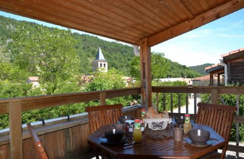 a table on a porch with a view of a church at Chalet Montana 4 pers in Roquefeuil