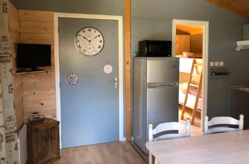 a kitchen with a clock on the wall and a refrigerator at Chalet Montana pmr 4 pers in Roquefeuil