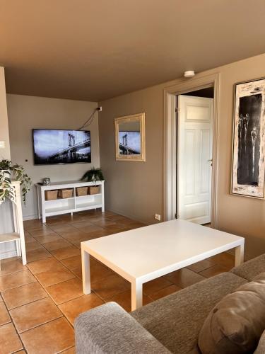 a living room with a white table and a tv at Bright and centrally studio with Oceanview in Kristiansand