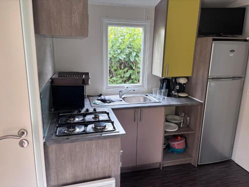a small kitchen with a sink and a stove at Mobil-home climatisé 4 pers in Roquefeuil
