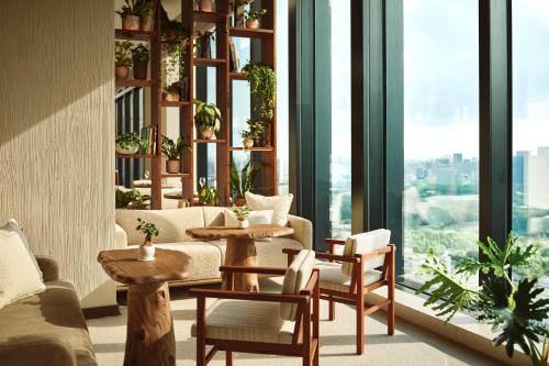 a living room with tables and chairs and windows at 1 Hotel Tokyo in Tokyo