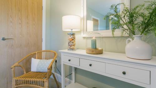 a room with a dresser with a candle and a chair at Trecastell in Rhosneigr