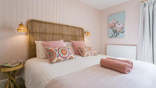 a bed with pink pillows and a pink towel on it at Trecastell in Rhosneigr