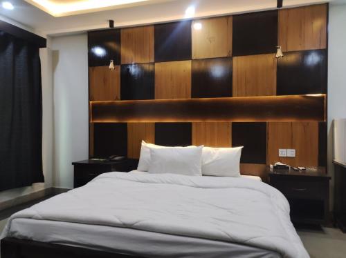 a bedroom with a large bed with a wooden headboard at Osma Living Apartment Peshawar in Peshawar