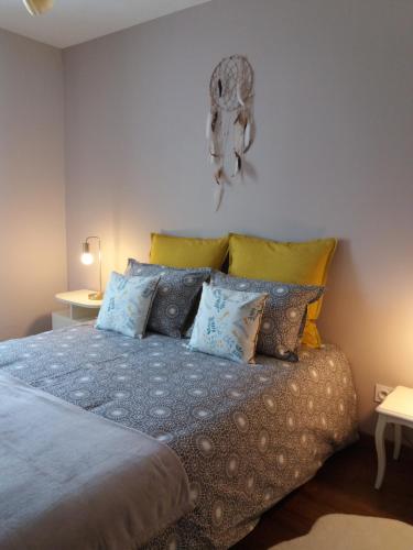 Schlafzimmer mit einem Bett mit blauen und gelben Kissen in der Unterkunft La Valériane in Moyeuvre-Grande