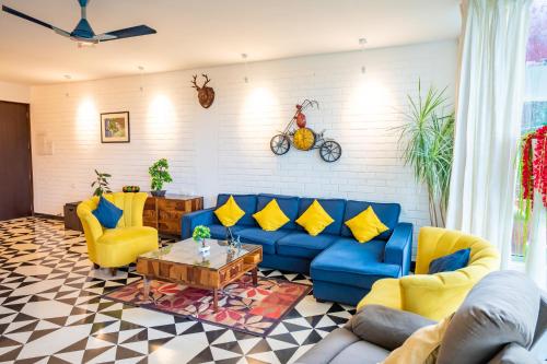 a living room with a blue couch and yellow chairs at Magnolia by Da Alohas El Arbol at Candolim in Nerul