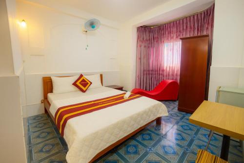 Una habitación de hotel con una cama y una silla roja. en Trung Bảo Hotel, en Ho Chi Minh