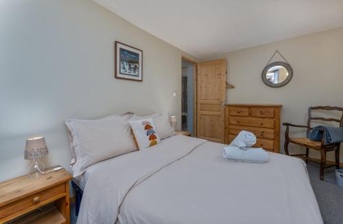 una camera da letto con un letto bianco e una cassettiera in legno di Près des Forts a Briançon