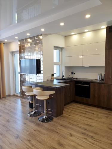 a large kitchen with a counter and stools in it at Cozy One-Bedroom Retreat in Klaipėda I Cohost in Melnragė