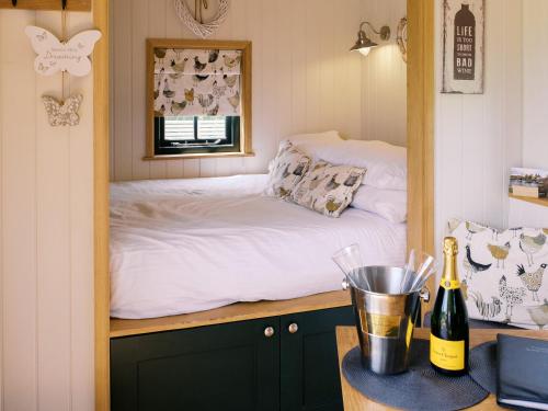 a bedroom with a bed and a bottle of champagne at Poppie's Shepherds Hut at Shepherds Lodge Retreat and Wellness in Nottingham