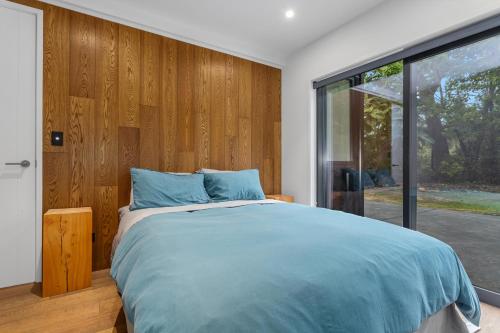 Un dormitorio con una cama y una ventana grande. en Treetop Hideaway - Ohope Holiday home, en Ohope Beach