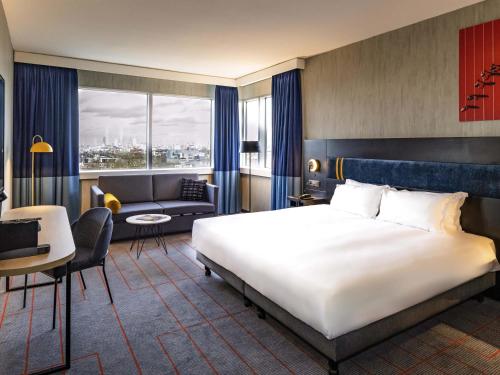 a bedroom with a large bed and a living room at Mercure Antwerp City South in Antwerp