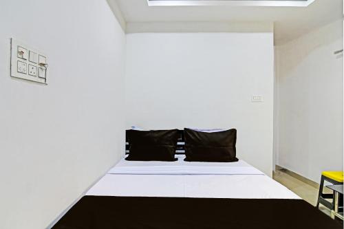 a bedroom with a white bed with black pillows at Hotel O Top 22 in Ballygunge