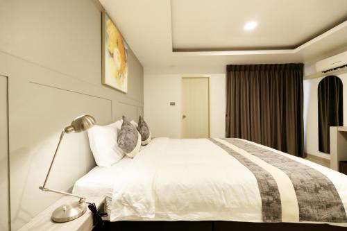 Un dormitorio con una cama blanca y una lámpara. en UTD8 Hotel and Residence, en Bangkok