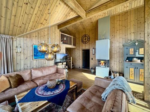 een woonkamer met een bank en een tafel bij Modern cabin with panoramic view, sauna and fire pit in Espedalen