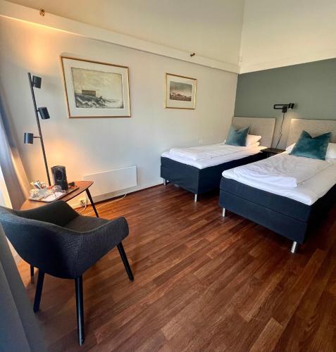 ein Hotelzimmer mit zwei Betten und einem Stuhl in der Unterkunft Saltstraumen Hotel og Fjordhytter in Bodø