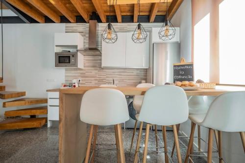 a kitchen with a table and white stools at Apartamento en casco histórico Exclusivo con AC in San Martín de Valdeiglesias