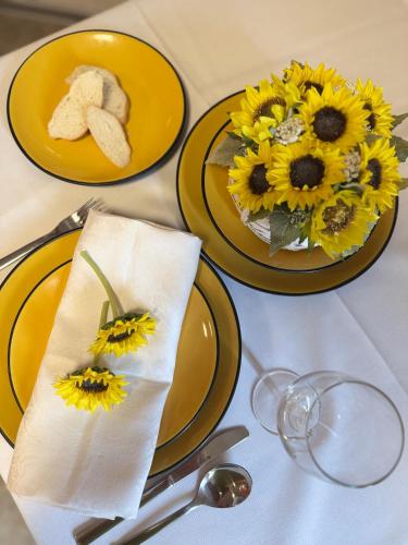 Una mesa con platos amarillos y girasoles encima. en Hotel Junior Poděbrady, en Poděbrady