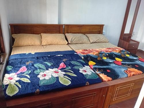 a bed with a blue blanket with flowers on it at Blessed guest Nuwara eliya in Nikawatawana